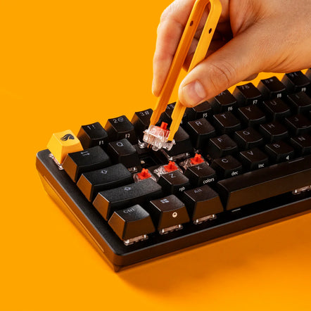 a hand holding a pair of tweezers over a keyboard