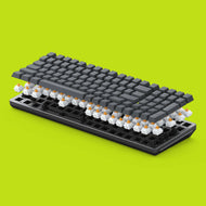 A Black GMMK 2 96% Barebones with GPBT Black Ash Keycaps is shown in an exploded view, revealing Glorious Panda switches beneath the keys. The background is a bright lime green.