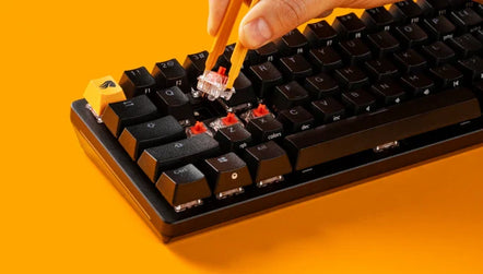 a hand holding a pair of tweezers over a keyboard